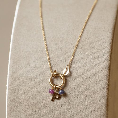 Collana rolo con chiusura a molla, pietre naturali e lettera – oro giallo 750